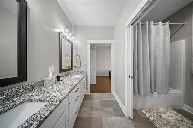 690 SW T Hwy, Holden, MO 64040 - bathroom with double vanity, bathing tub / shower combination, baseboards, and stone finish flooring