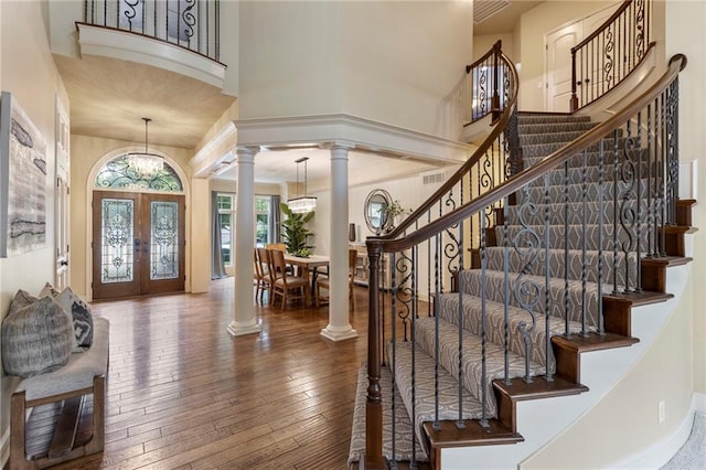 9300 W 156th Pl, Overland Park, KS 66221 - foyer entrance featuring a towering ceiling, decorative columns, french doors, a chandelier, and hardwood / wood-style flooring