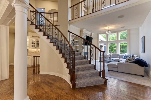 9300 W 156th Pl, Overland Park, KS 66221 - stairway with ornate columns, hardwood / wood-style flooring, a high ceiling, and baseboards