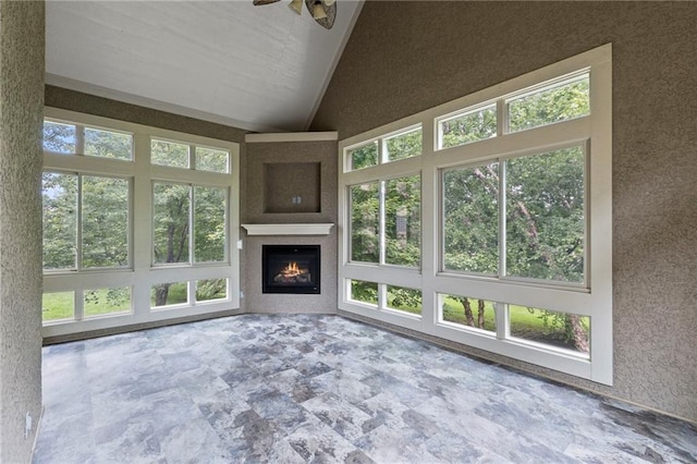 9300 W 156th Pl, Overland Park, KS 66221 - unfurnished living room with stone finish flooring, ceiling fan, vaulted ceiling, and a warm lit fireplace