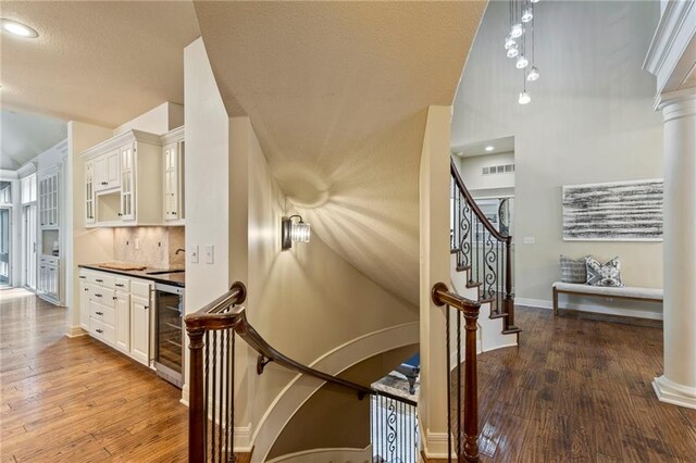 9300 W 156th Pl, Overland Park, KS 66221 - stairs featuring beverage cooler, hardwood / wood-style flooring, baseboards, and decorative columns