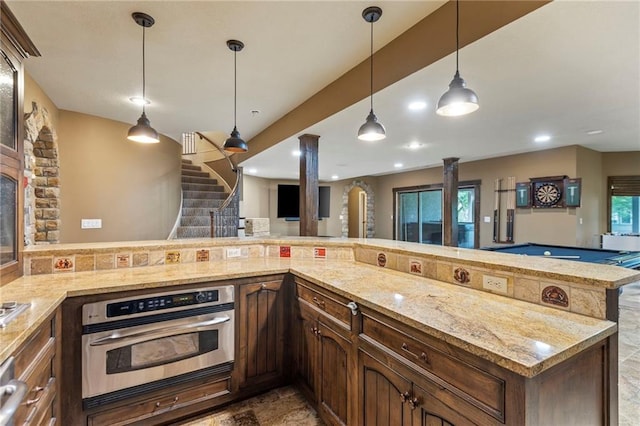 9300 W 156th Pl, Overland Park, KS 66221 - kitchen featuring stainless steel oven, ornate columns, light stone countertops, hanging light fixtures, and recessed lighting
