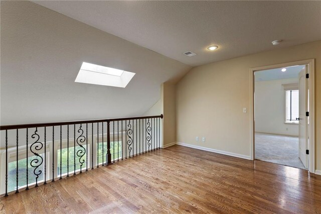 9300 W 156th Pl, Overland Park, KS 66221 - bonus room featuring a skylight, wood finished floors, vaulted ceiling, baseboards, and recessed lighting