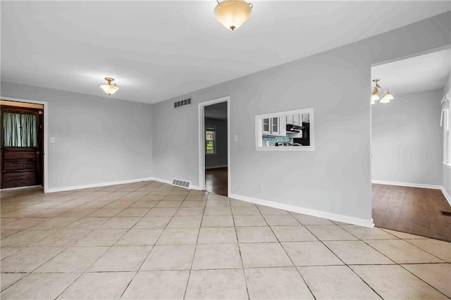 3218 NE 47th St, Kansas City, MO 64119 - spare room featuring light tile patterned floors, a chandelier, and baseboards