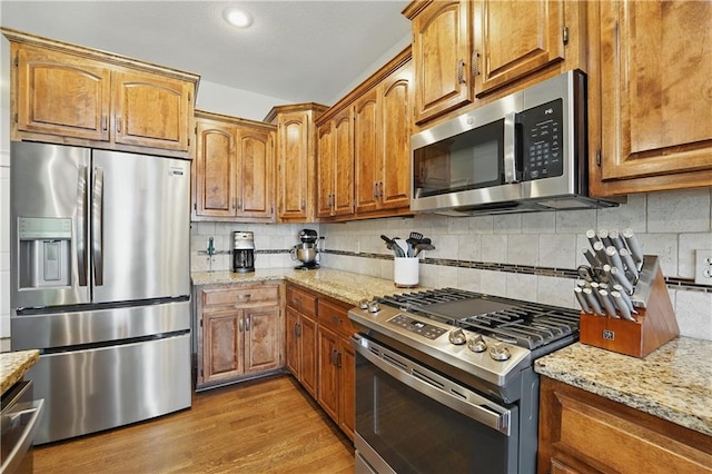 1104 NW 109th St, Kansas City, MO 64155 - kitchen featuring stainless steel appliances, brown cabinets, and wood finished floors
