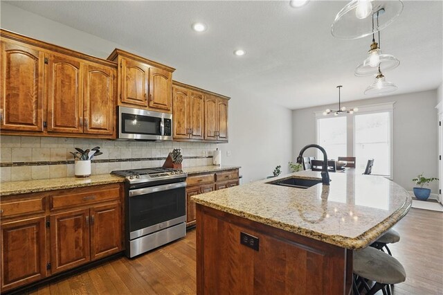 1104 NW 109th St, Kansas City, MO 64155 - kitchen featuring stainless steel appliances, a sink, a breakfast bar area, decorative backsplash, and dark wood finished floors