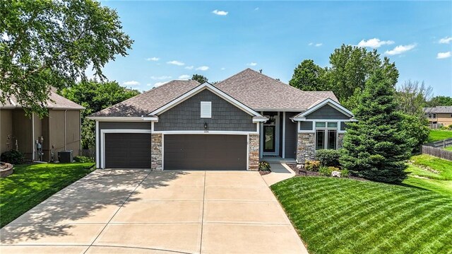 1104 NW 109th St, Kansas City, MO 64155 - craftsman-style home with a garage, a front yard, central air condition unit, and stone siding