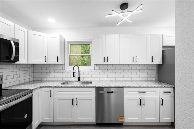 1419 Washington Blvd, Kansas City, KS 66102 - kitchen featuring appliances with stainless steel finishes, a sink, decorative backsplash, and white cabinets