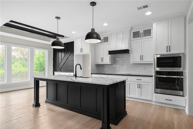 14278 S Houston St, Olathe, KS 66061 - kitchen featuring appliances with stainless steel finishes, a sink, light wood-style floors, backsplash, and an island with sink