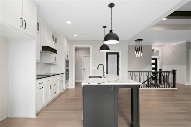 14278 S Houston St, Olathe, KS 66061 - kitchen with a sink, light wood finished floors, white cabinets, an island with sink, and recessed lighting