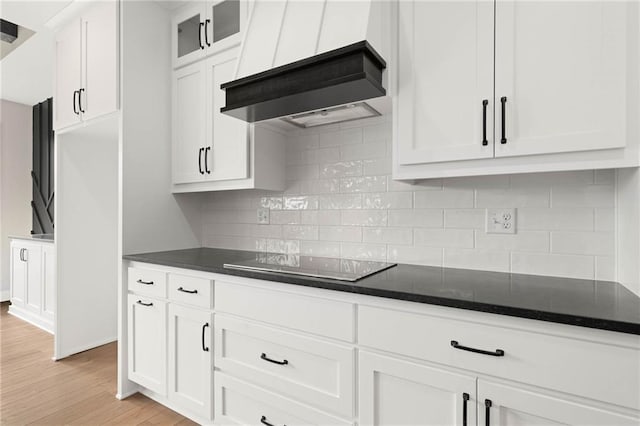 14278 S Houston St, Olathe, KS 66061 - kitchen featuring black electric stovetop, custom range hood, white cabinetry, light wood finished floors, and backsplash