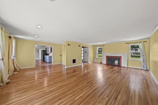 2306 Red Bridge Ter, Kansas City, MO 64131 - unfurnished living room with light wood-style flooring, a brick fireplace, baseboards, ornamental molding, and recessed lighting