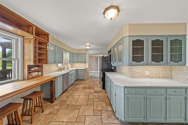 2306 Red Bridge Ter, Kansas City, MO 64131 - kitchen featuring appliances with stainless steel finishes, open shelves, light countertops, stone tile flooring, and backsplash