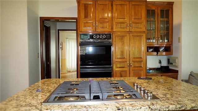 5500 NW 62nd St, Kansas City, MO 64151 - kitchen featuring stainless steel gas stovetop, brown cabinets, glass insert cabinets, and light stone countertops