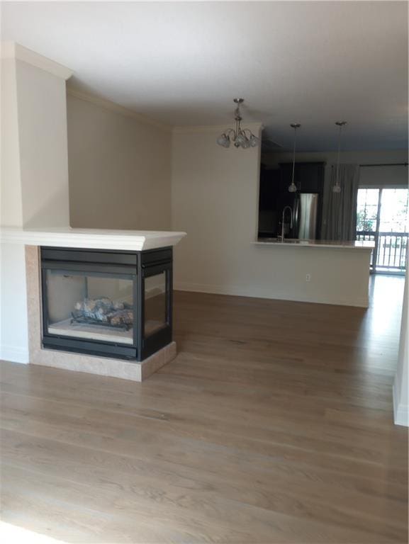 15829 W Robinson St, Overland Park, KS 66223 - unfurnished living room featuring a multi sided fireplace, wood finished floors, baseboards, a chandelier, and a sink