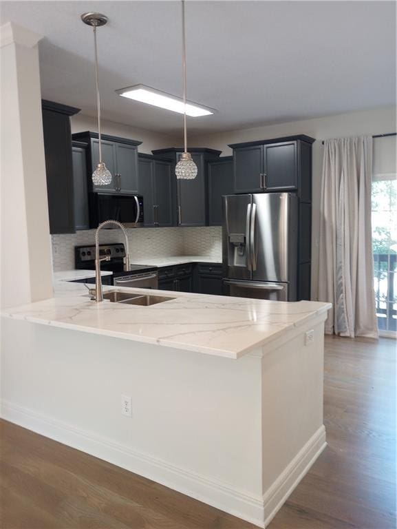 15829 W Robinson St, Overland Park, KS 66223 - kitchen featuring appliances with stainless steel finishes, a peninsula, light stone counters, and decorative backsplash