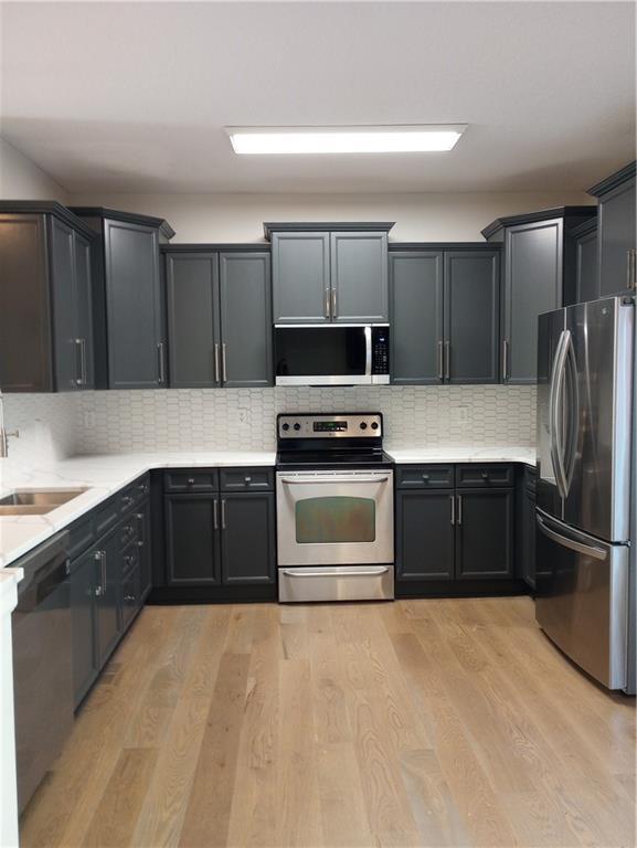15829 W Robinson St, Overland Park, KS 66223 - kitchen with stainless steel appliances, a sink, light countertops, and light wood-style flooring