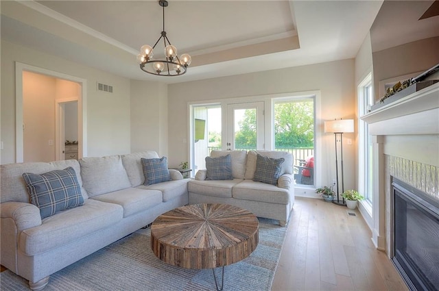 24129 W 95th St, Lenexa, KS 66227 - living area featuring a chandelier, a fireplace, light wood-style flooring, and a tray ceiling