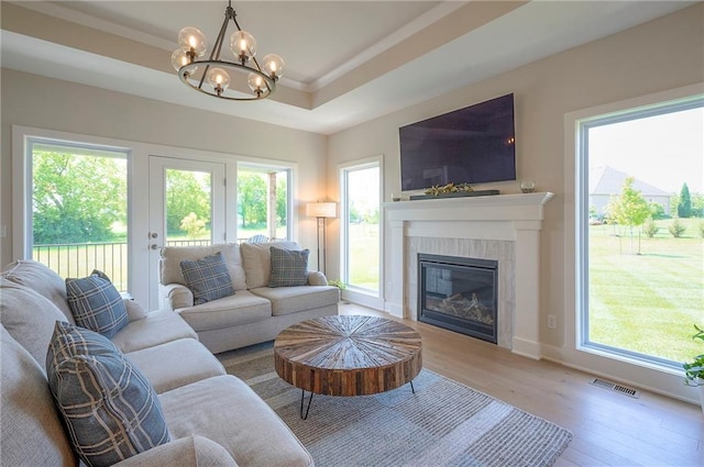 24129 W 95th St, Lenexa, KS 66227 - living room featuring wood finished floors, a chandelier, plenty of natural light, a tile fireplace, and ornamental molding