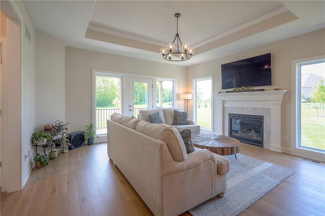 24129 W 95th St, Lenexa, KS 66227 - living room featuring a raised ceiling, light wood-style flooring, a chandelier, and healthy amount of natural light