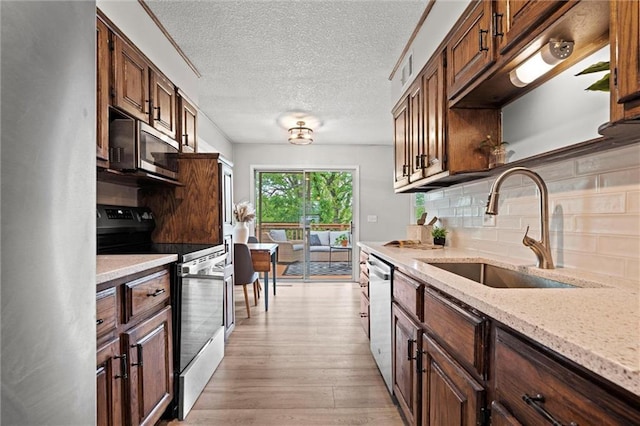 6525 County Line Rd, Shawnee, KS 66216 - kitchen featuring stainless steel appliances, light wood finished floors, tasteful backsplash, a textured ceiling, and light stone counters