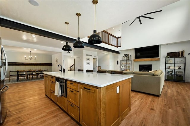24905 W 57th St, Shawnee, KS 66226 - kitchen featuring brown cabinets, light wood-type flooring, a sink, a large island, and decorative light fixtures