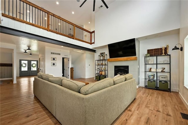 24905 W 57th St, Shawnee, KS 66226 - living area with a fireplace, a ceiling fan, baseboards, light wood finished floors, and a towering ceiling