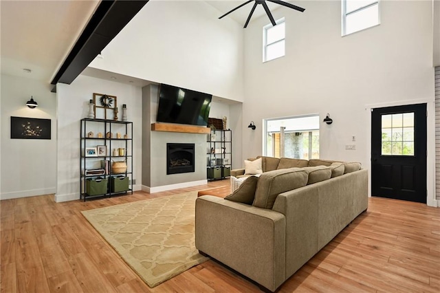 24905 W 57th St, Shawnee, KS 66226 - living room with ceiling fan, light wood-style flooring, a fireplace, a high ceiling, and baseboards