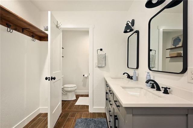 24905 W 57th St, Shawnee, KS 66226 - full bathroom with wood finish floors, toilet, double vanity, and baseboards