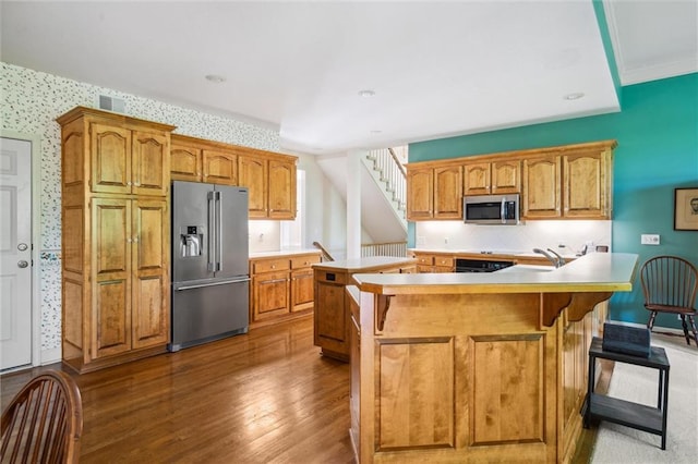 14913 W 72nd St, Shawnee, KS 66216 - kitchen with appliances with stainless steel finishes, wallpapered walls, dark wood-style flooring, a kitchen bar, and light countertops