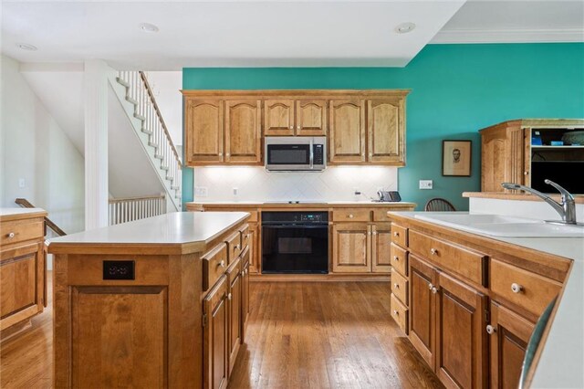 14913 W 72nd St, Shawnee, KS 66216 - kitchen with black oven, stainless steel microwave, a center island, wood finished floors, and light countertops