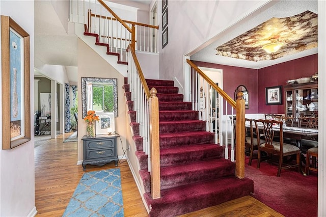 1515 Fox Run Ln, Raymore, MO 64083 - staircase featuring wood finished floors, a towering ceiling, and baseboards