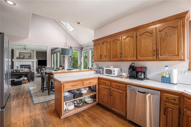1515 Fox Run Ln, Raymore, MO 64083 - kitchen featuring dishwasher, a peninsula, light countertops, brown cabinetry, and tasteful backsplash