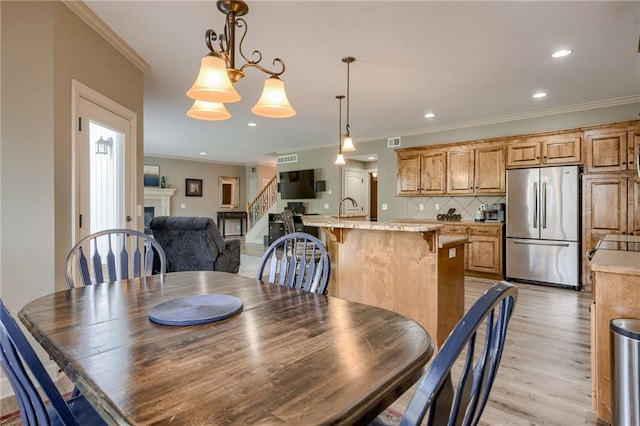 2208 SW Hawk View Rd, Lees Summit, MO 64082 - dining area with stairs, crown molding, a fireplace, light wood-type flooring, and recessed lighting