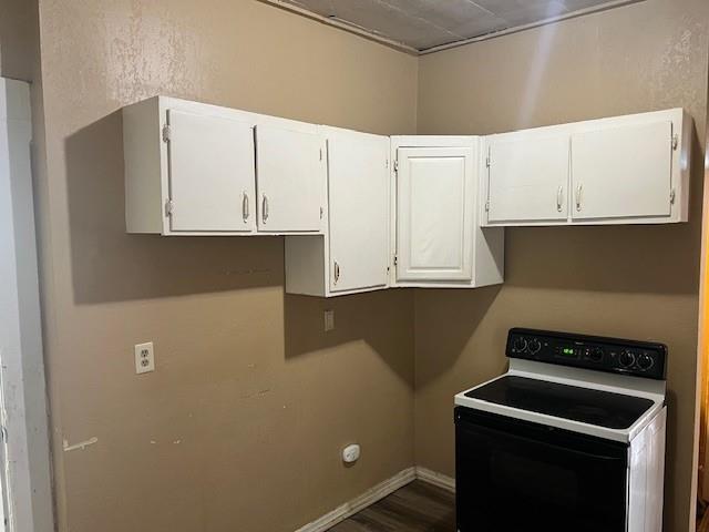 515 N 11th St, Saint Joseph, MO 64501 - kitchen with electric range oven, dark wood-style flooring, white cabinetry, and baseboards