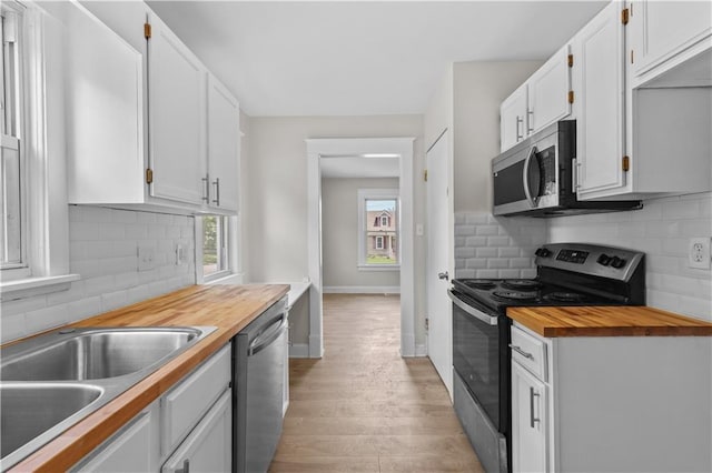 2100 S Scott Ave, Independence, MO 64052 - kitchen with appliances with stainless steel finishes, wood counters, tasteful backsplash, white cabinetry, and light wood-style floors