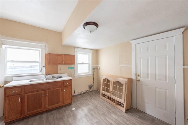 1129 Metropolitan Ave, Kansas City, KS 66103 - kitchen featuring a sink, brown cabinetry, light wood finished floors, and light countertops