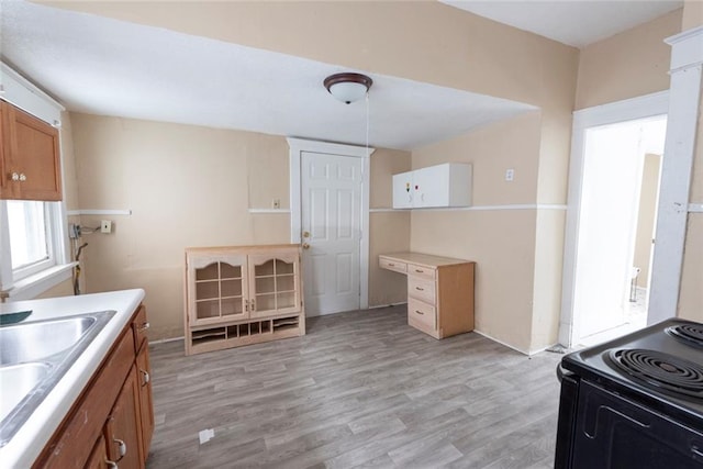 1129 Metropolitan Ave, Kansas City, KS 66103 - kitchen featuring light wood-style flooring, black range with electric cooktop, light countertops, a sink, and brown cabinetry