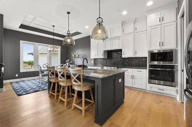 9412 Aurora St, Lenexa, KS 66220 - kitchen featuring appliances with stainless steel finishes, a tray ceiling, white cabinetry, decorative backsplash, and recessed lighting