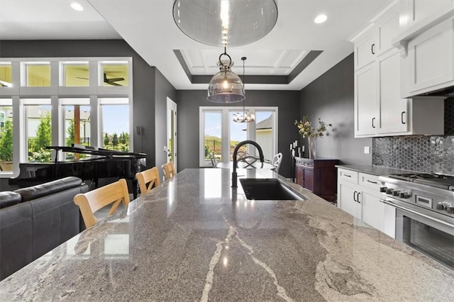9412 Aurora St, Lenexa, KS 66220 - kitchen featuring a sink, high end stainless steel range oven, a chandelier, white cabinets, and decorative backsplash