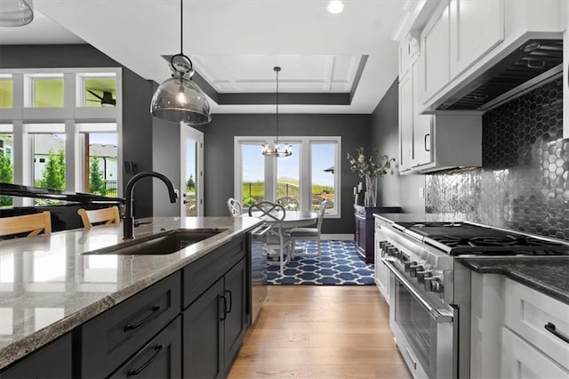9412 Aurora St, Lenexa, KS 66220 - kitchen with stainless steel appliances, a sink, a chandelier, under cabinet range hood, and dark stone countertops