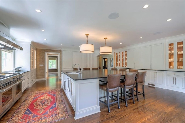 1055 W 54th St, Kansas City, MO 64112 - kitchen featuring double oven range, dark countertops, a kitchen island with sink, white cabinetry, and dark wood-type flooring