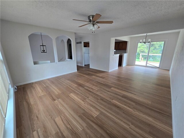 1506 N Holland Ct, Independence, MO 64056 - unfurnished living room with wood finished floors, a textured ceiling, a chandelier, and ceiling fan