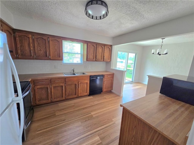 1506 N Holland Ct, Independence, MO 64056 - kitchen featuring black dishwasher, light wood-type flooring, a textured ceiling, freestanding refrigerator, and decorative backsplash
