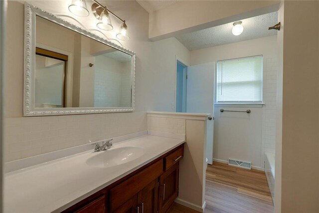 1506 N Holland Ct, Independence, MO 64056 - bathroom with vanity, wood finished floors, shower / washtub combination, and a textured ceiling