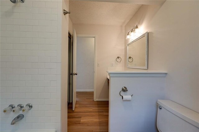 1506 N Holland Ct, Independence, MO 64056 - bathroom with wood finished floors, vanity, a textured ceiling, and shower / bathtub combination
