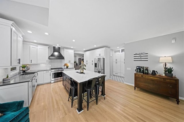 8102 W 153rd St, Overland Park, KS 66223 - kitchen featuring appliances with stainless steel finishes, wall chimney exhaust hood, decorative backsplash, light wood-type flooring, and white cabinets