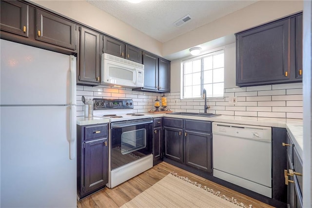 2406 Alabama St Unit 9D, Lawrence, KS 66046 - kitchen featuring white appliances, light countertops, backsplash, light wood-style flooring, and a textured ceiling