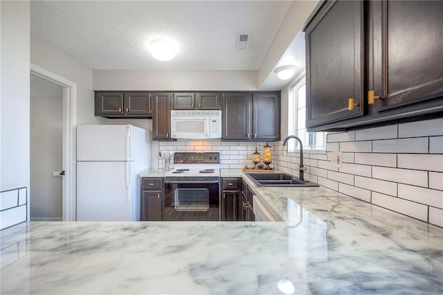 2406 Alabama St Unit 9D, Lawrence, KS 66046 - kitchen with white appliances, decorative backsplash, dark brown cabinetry, light stone counters, and a textured ceiling