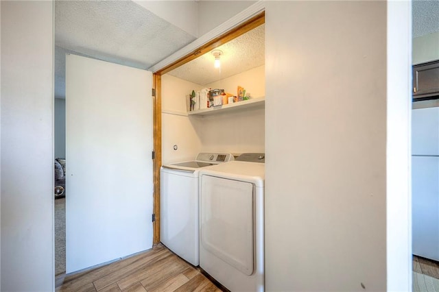 2406 Alabama St Unit 9D, Lawrence, KS 66046 - laundry area with washing machine and clothes dryer, light wood-type flooring, and a textured ceiling